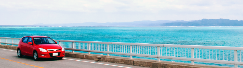 沖縄の海沿いを走る赤い車